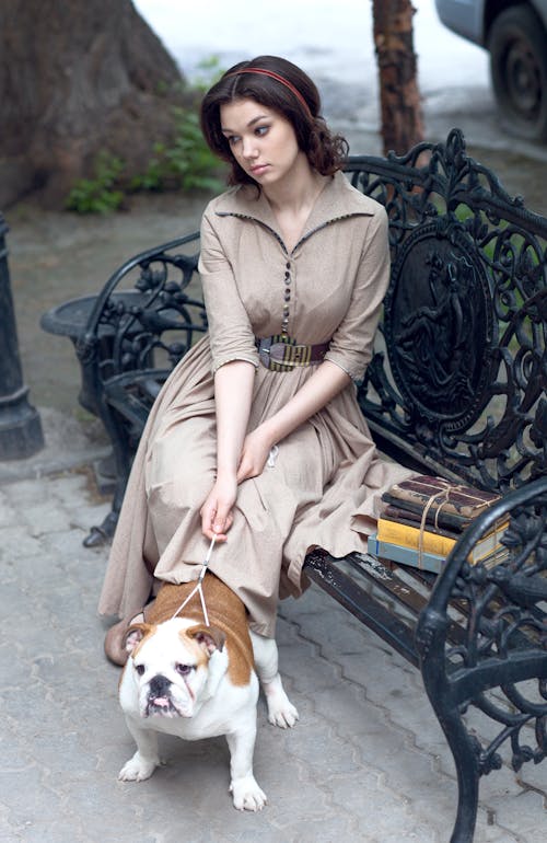 Woman in Brown Dress Holding the Leash of a Dog