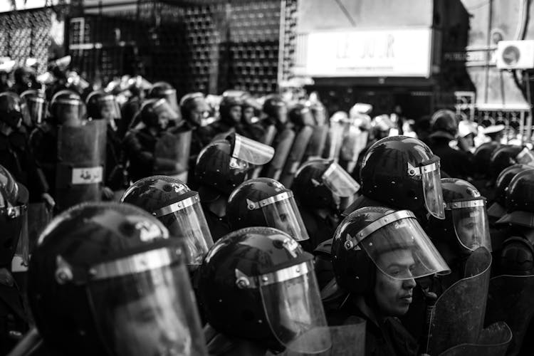 Grayscale Photo Of People With Shields And Helmets 