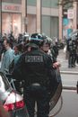 执行抗议任务时，戴着头盔和盾牌、面目全非的警察站在汽车和戴着面具的抗议者附近的后视图