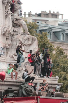 Group of diverse protesters with hands up and sign standing on monument and making demands