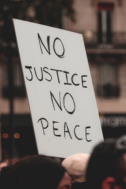 Group of crop peaceful protesters at Black Lives Matter demonstration with handwritten poster reading No Justice No Peace
