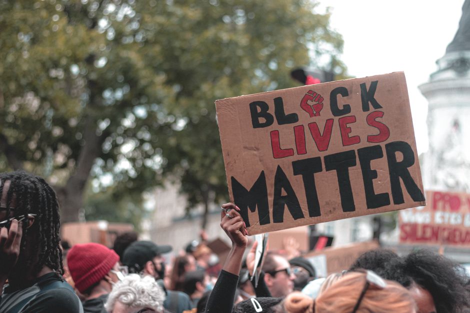 Crowd of people gathering together for protest holding up handmade cardboard signs with Black lives matter inscription