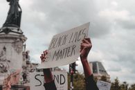在阴云密布的天空下，一场声势浩大的“黑人生命至上”抗议活动中，人们高举着标语牌