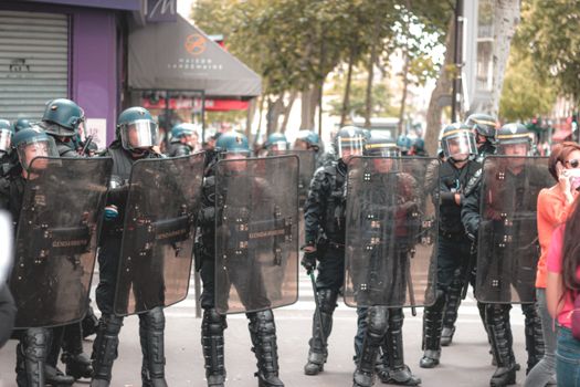 一群头戴钢盔、身穿警服的士兵沿着街道行进，保护着附近抗议的人们