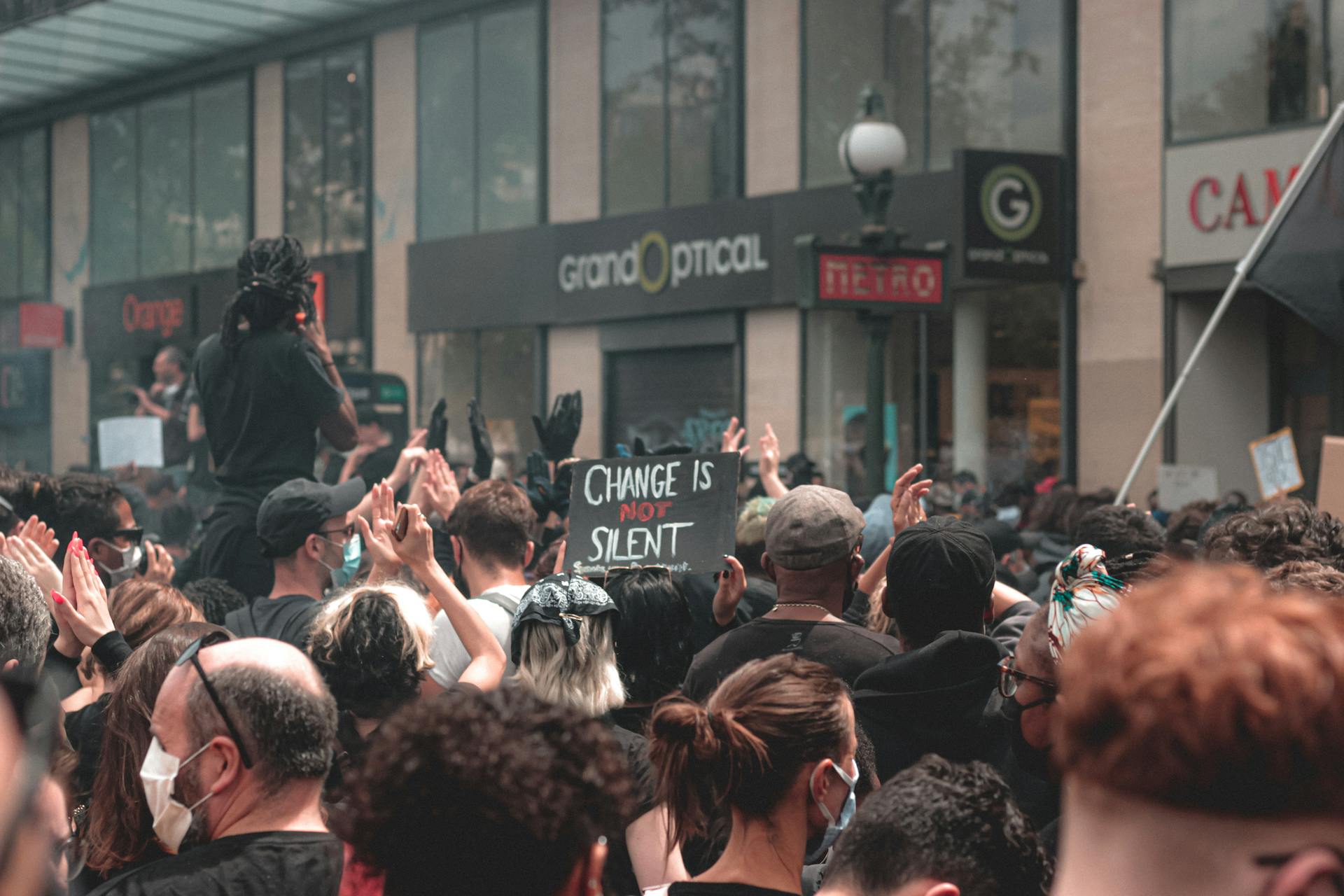 A diverse crowd at a peaceful protest with banners advocating for social change in an urban environment.