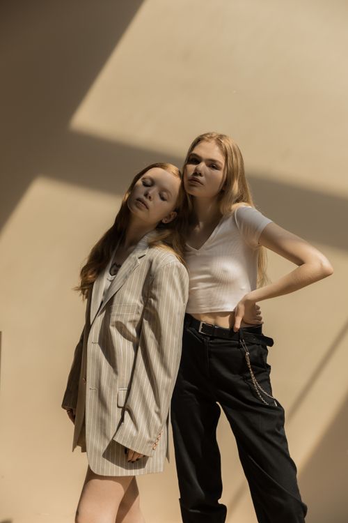 Free Two stylish women pose in dramatic sunlight, showcasing modern fashion and relaxed aesthetics. Stock Photo