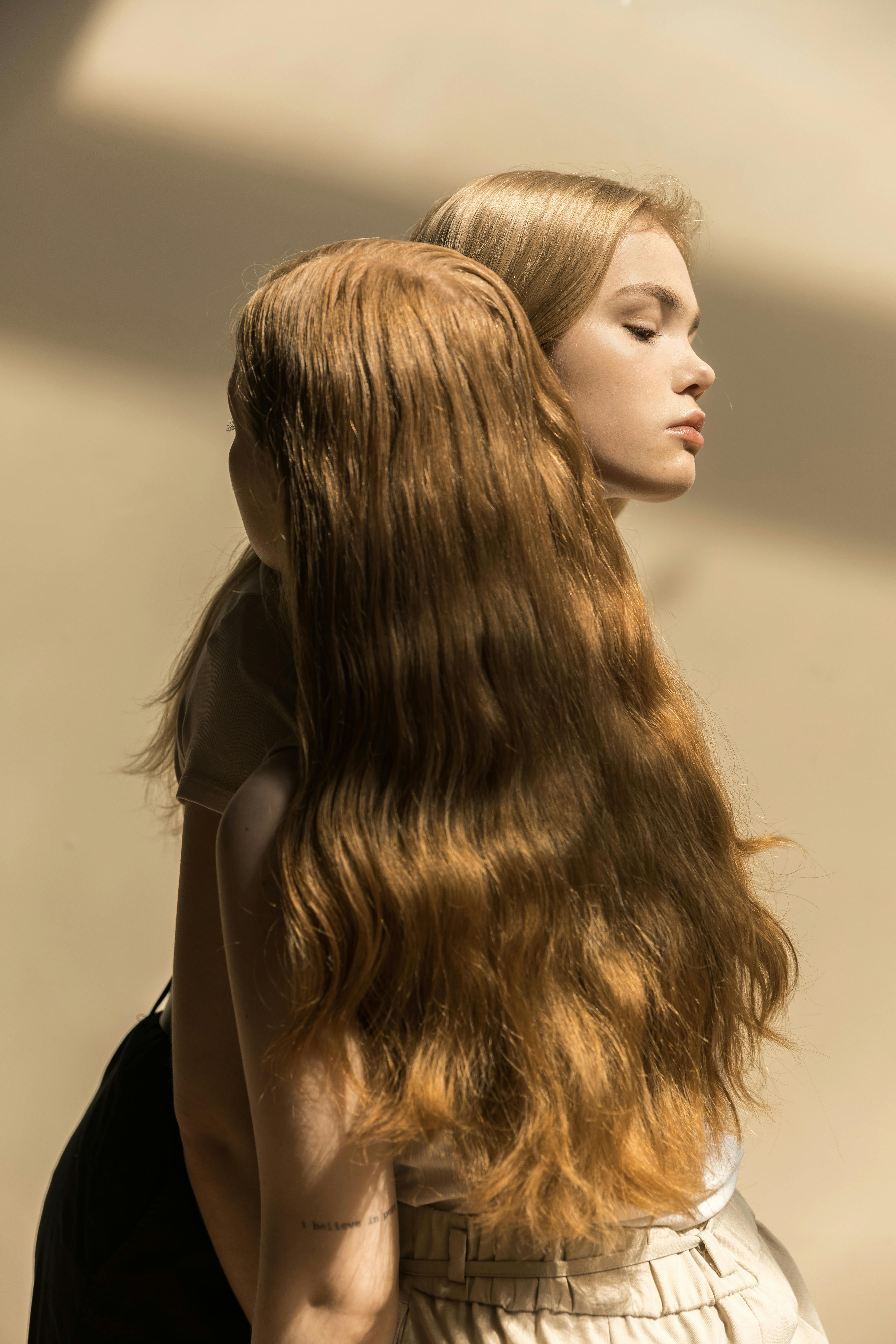 a person with long blond hair standing close together with a woman