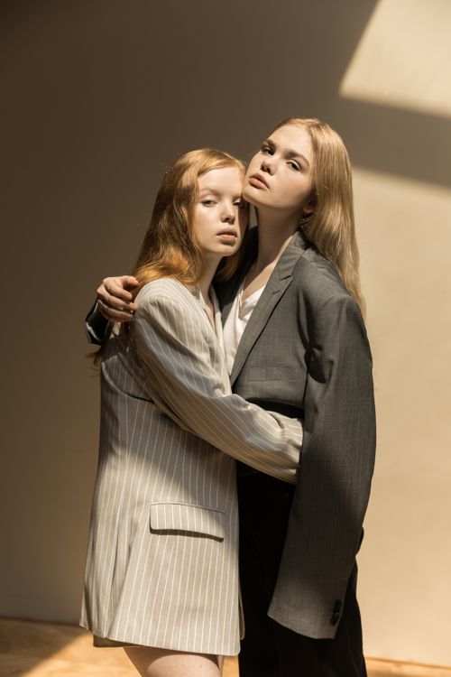 Free Fashionable studio portrait of two women posing in suits, with dramatic lighting. Stock Photo