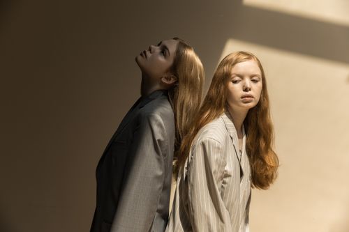 Free Artistic portrait of two women in stylish suits with playful poses and dramatic lighting. Stock Photo