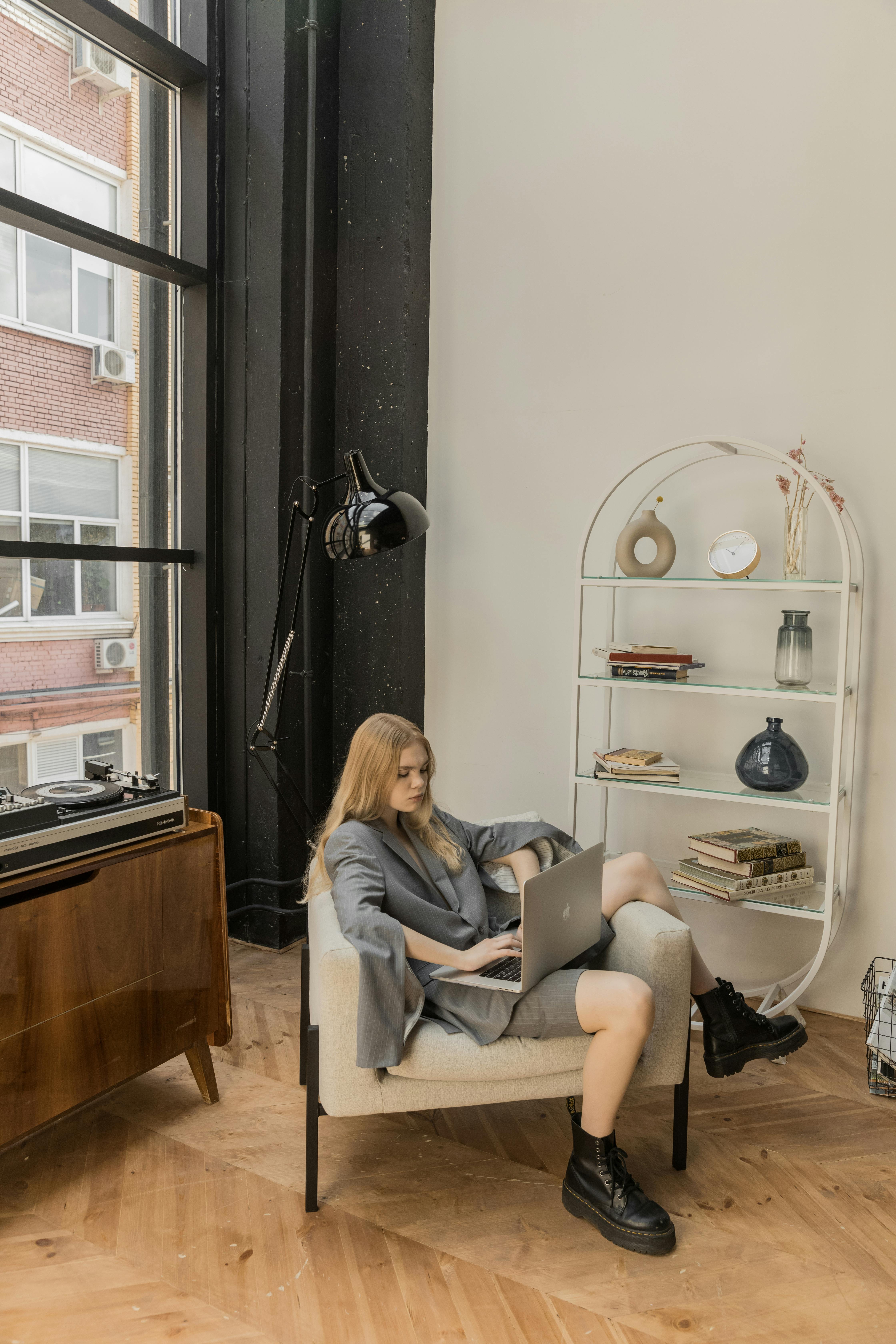 在现代公寓里，一位白人妇女坐在椅子上使用笔记本电脑，日光流淌