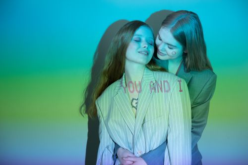 Free A loving LGBTQ couple embracing, illuminated by colorful neon light with the text 'You and I' overlayed. Stock Photo