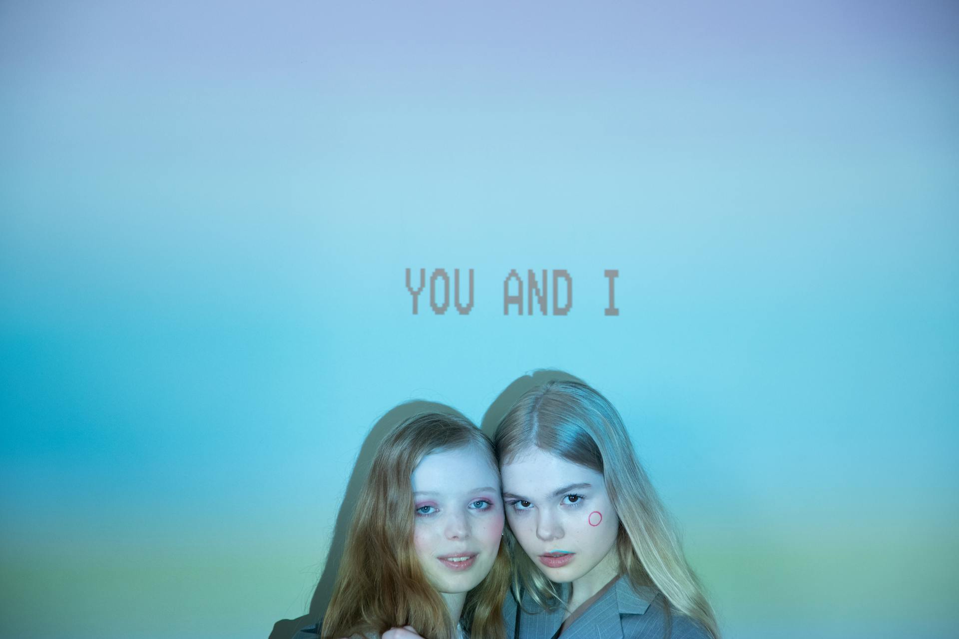 Two women in front of a colorful background with the text 'YOU AND I'.