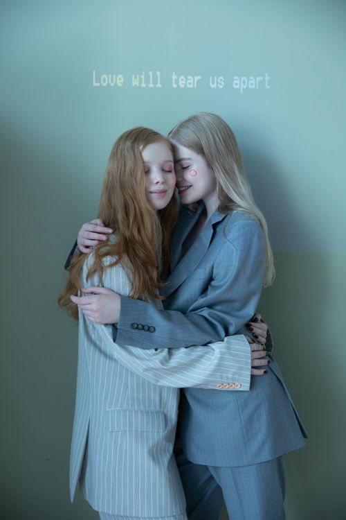 Free Two women in suits embrace warmly, expressing affection and style in an intimate setting. Stock Photo