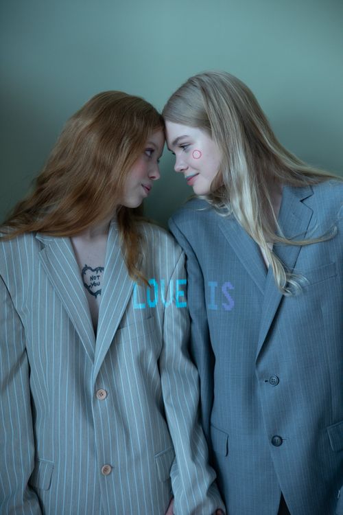 Free Two women in suits share a tender moment, showcasing affection and connection. Stock Photo