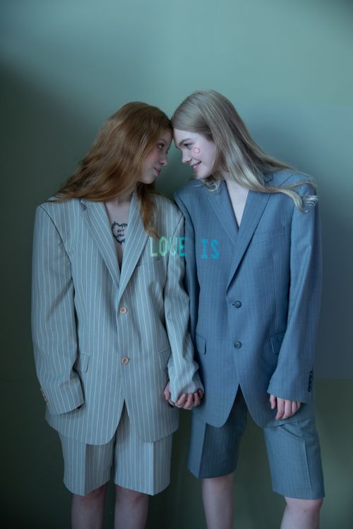 Free Two models standing closely, holding hands and wearing suits, symbolizing love. Stock Photo