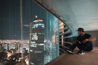 夜晚，一个人坐在屋顶上，俯瞰着灯火通明的摩天大楼