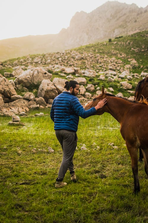 Man in Blue Jacket Petting a Horse