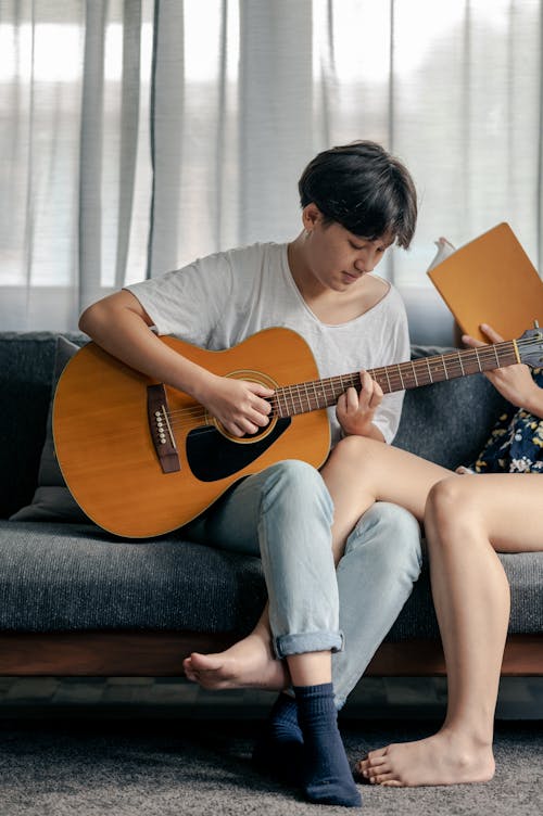 Kostenloses Stock Foto zu couch, frau, gitarre spielen