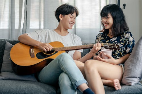Free Woman Playing Guitar Beside a Person Stock Photo