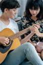 Woman in White Tank Top Playing Acoustic Guitar