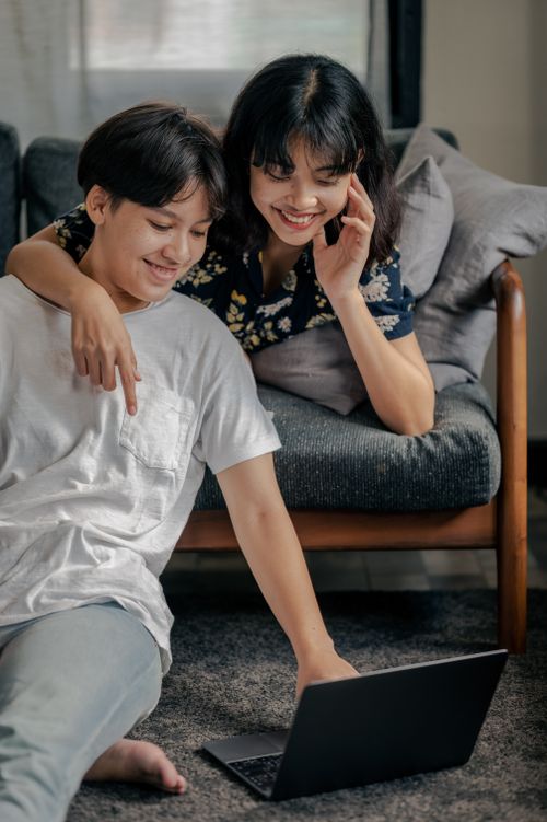 Free Smiling couple sitting indoors, enjoying a casual moment with a laptop. Stock Photo