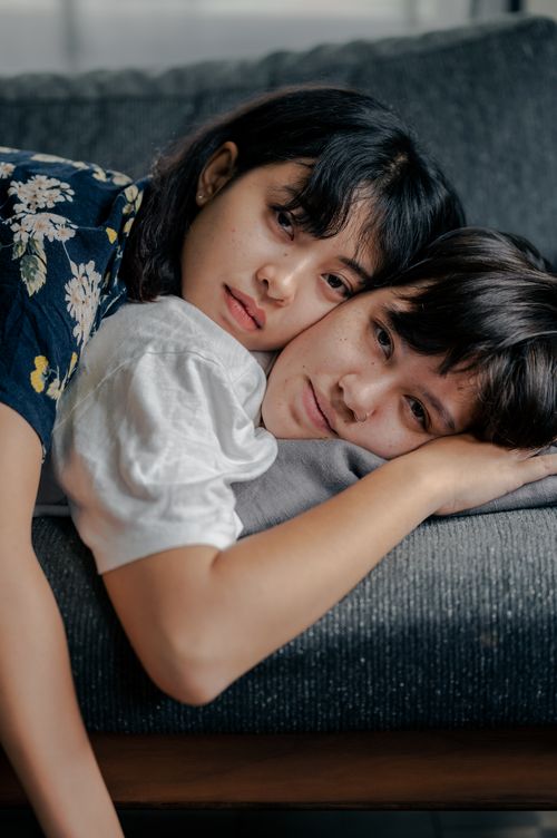 Free A serene and intimate portrait of two adults resting together on a couch, showcasing comfort and affection. Stock Photo