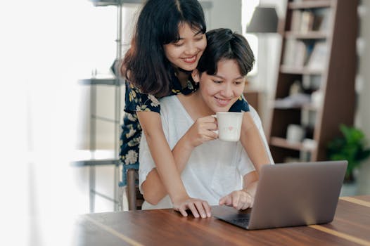 一对开朗的夫妇在室内一边浏览笔记本电脑，一边拥抱并一起享用咖啡