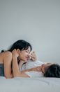 两个女人躺在室内的床上，分享着温柔而亲密的时刻
