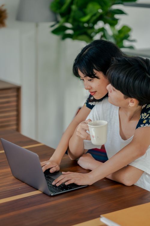 Free A couple shares a laptop, sipping coffee while working remotely in a cozy home setting. Stock Photo