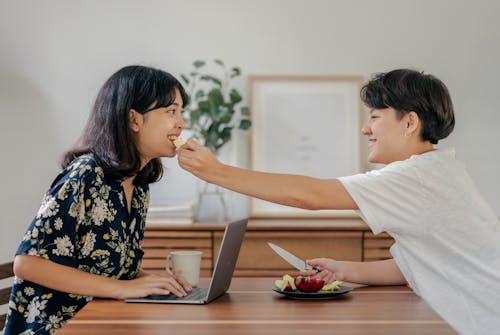 Photo of Couple Smiling While Sitting by the Wooden Table