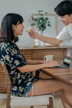 年轻夫妇在家轻松工作，用着笔记本电脑，喝着咖啡