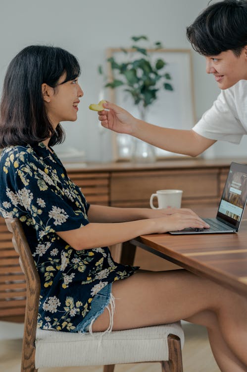 Free Woman in Floral Shirt Sitting on Chair While Using Laptop Stock Photo