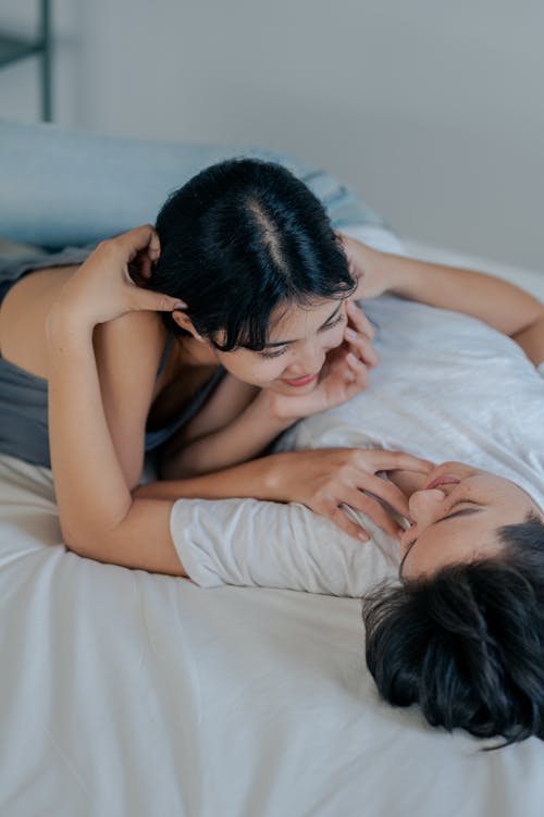 Couple Smiling While Lying on Bed