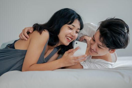 一对年轻夫妇在卧室里用智能手机快乐地分享了一个瞬间