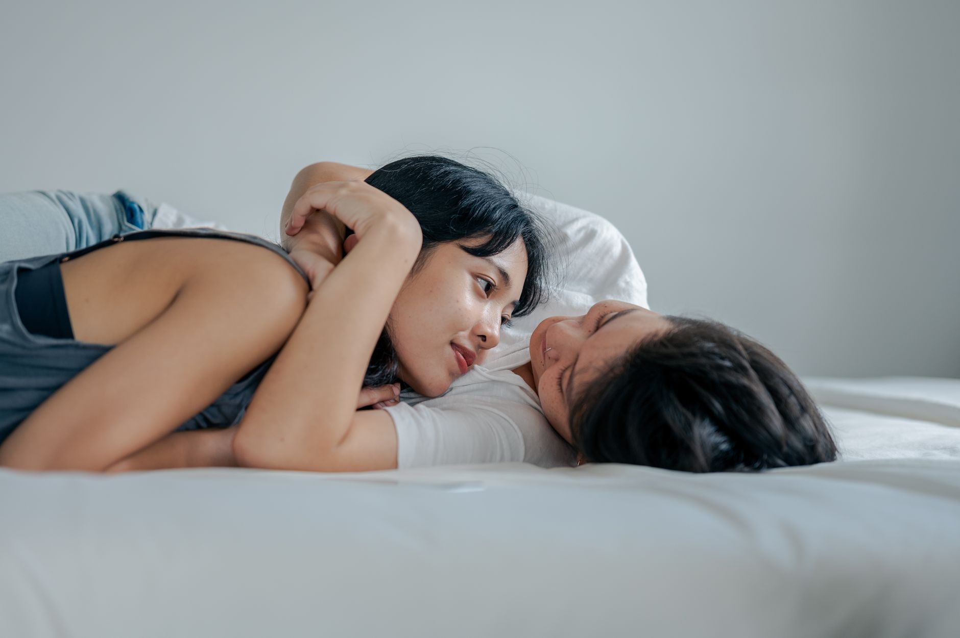 A joyful couple sharing a tender moment lying on a bed in a cozy, indoor setting.