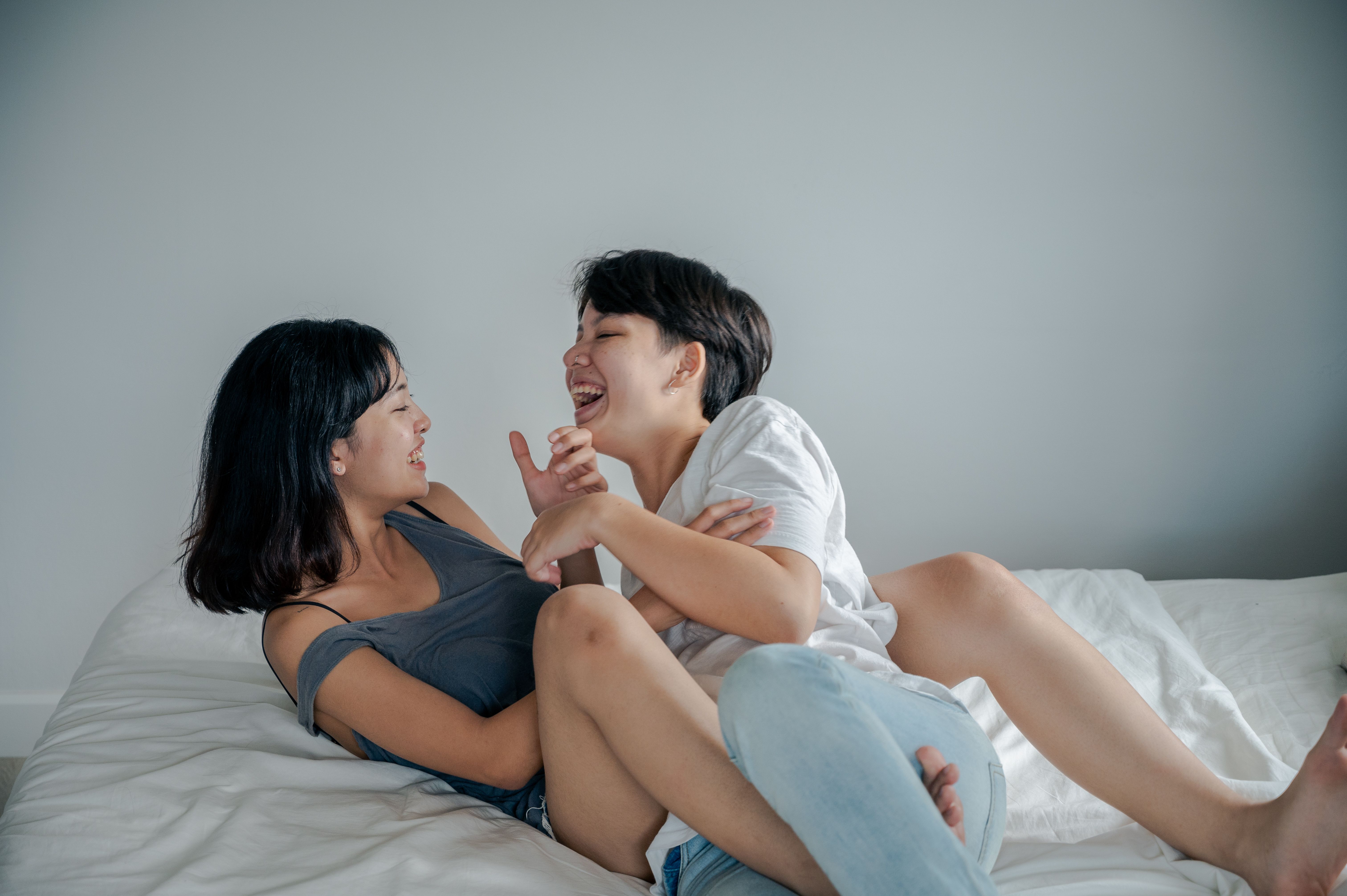 两个女人在室内的床上分享着快乐而亲密的时刻
