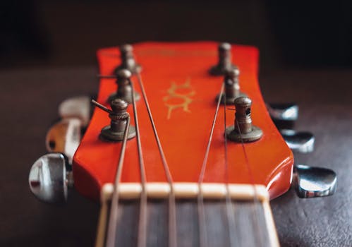 Detailed close-up of a red guitar headstock focusing on strings and tuning pegs.