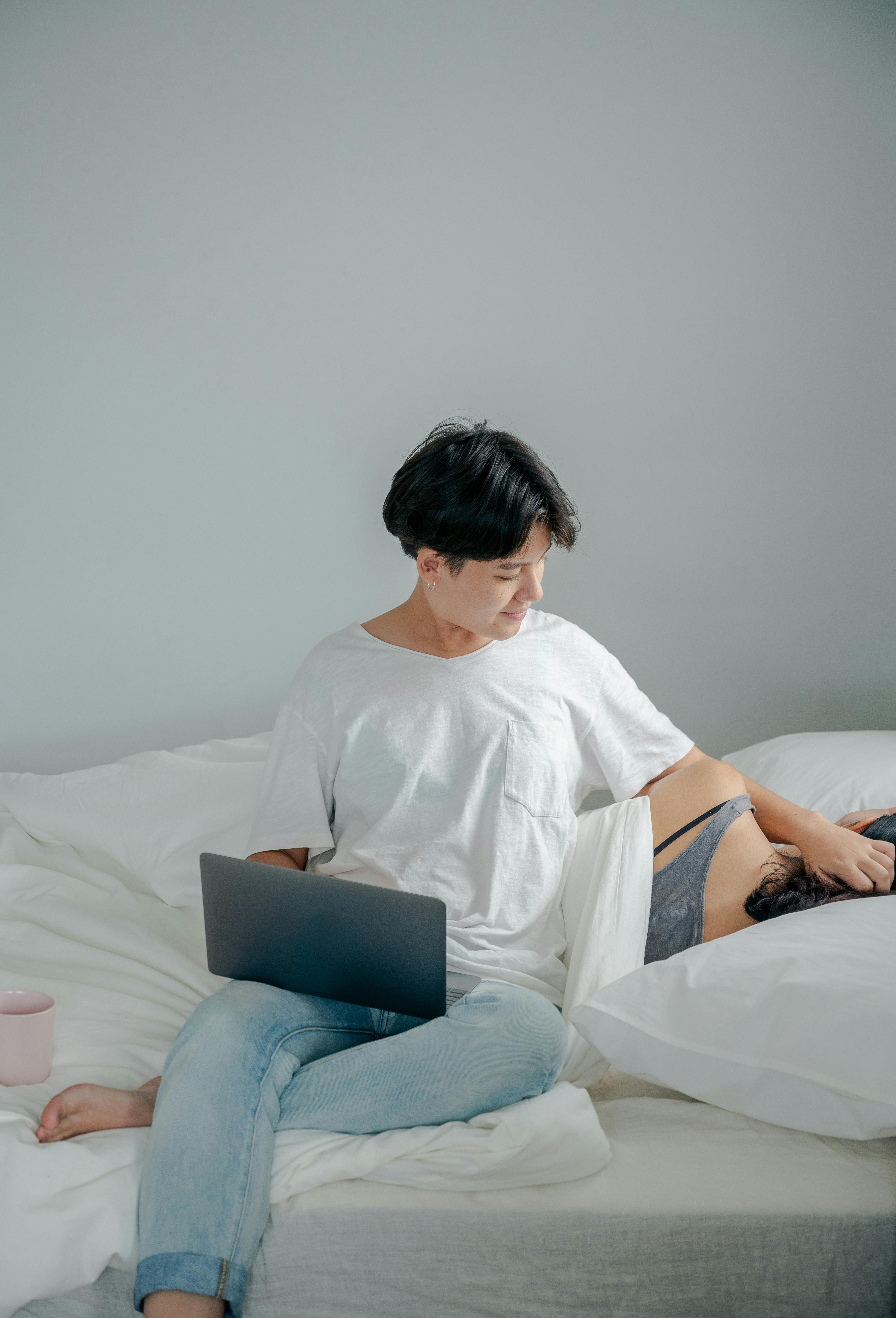 woman working on laptop stroking hair of her sleeping partner