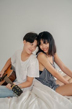 一对恩爱的夫妇在明亮的房间里，一起分享耳机和吉他，享受音乐