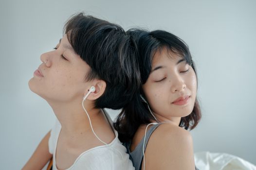 两个戴着耳机的女人闭着眼睛，沉浸在音乐中，共享着一段宁静的时光