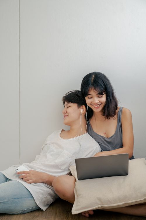 Free Two women enjoying leisure time together with a laptop and earphones, reflecting a cozy indoor atmosphere. Stock Photo