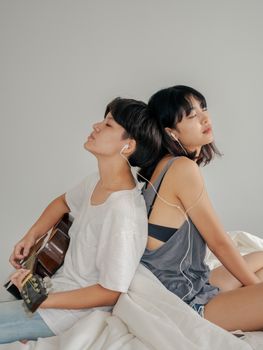 夫妇在室内分享耳机和吉他，一起享受音乐