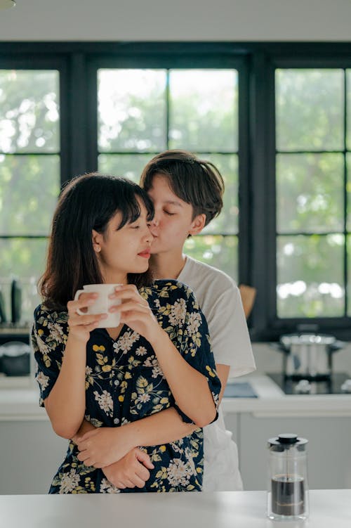 Free Photo of Couple Hugging While Holding Coffee Mug Stock Photo