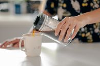 Person Pouring Water on White Ceramic Mug