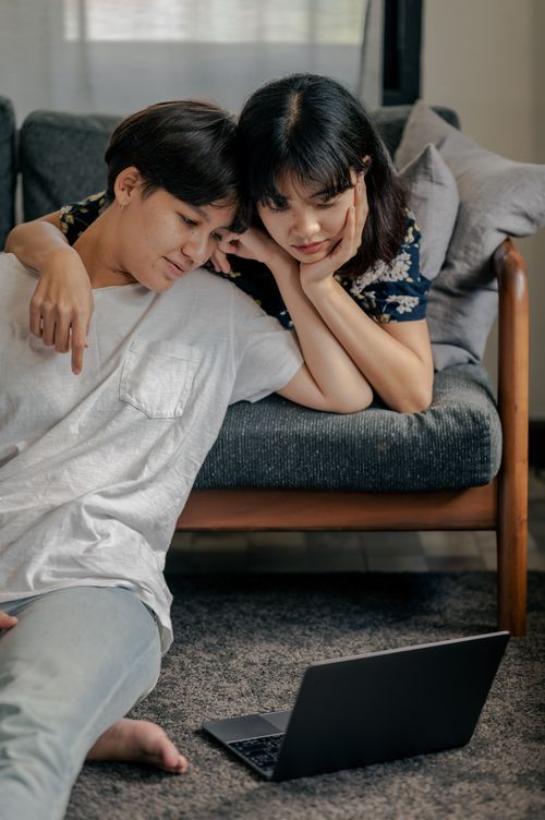 Free Young couple enjoying quality time on sofa watching laptop together. Stock Photo