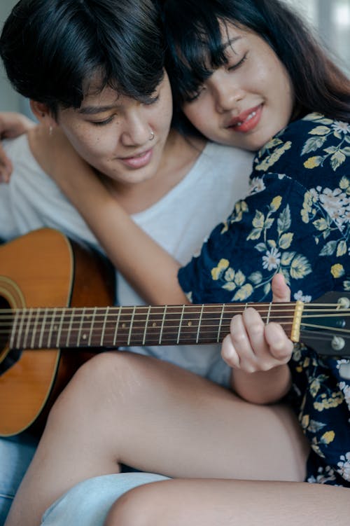 Photo of Woman Hugging Her Man While Playing Acoustic Guitar