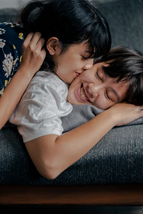 Free A joyful couple shares an affectionate moment on a sofa indoors, expressing love and happiness. Stock Photo