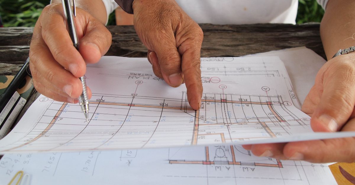 Dois profissionais analisando plantas e projetos sobre uma mesa de trabalho