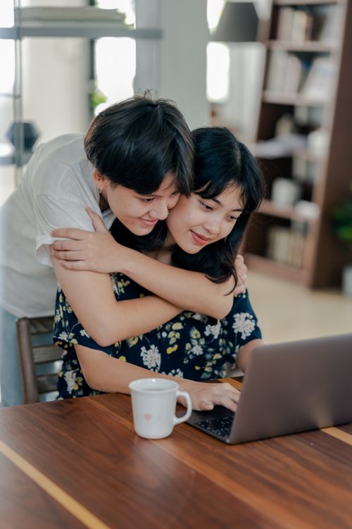 Free Happy couple enjoying a moment of affection while working on a laptop at home. Stock Photo