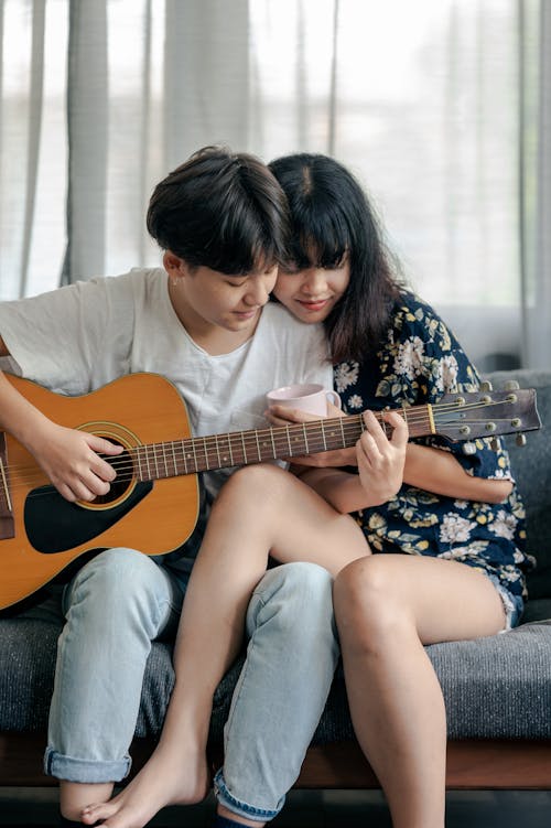 Free Photo of Man in White Shirt Playing Acoustic Guitar With Her Woman Stock Photo